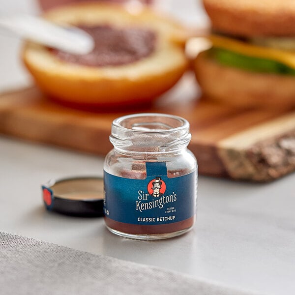 A single-serve Sir Kensington's Ketchup jar on a table.