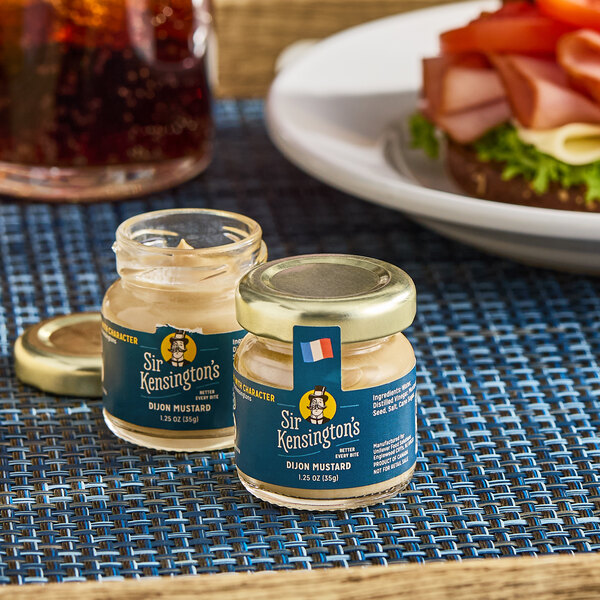 A pair of small glass jars of Sir Kensington's Dijon Mustard, each containing 1.25 oz.