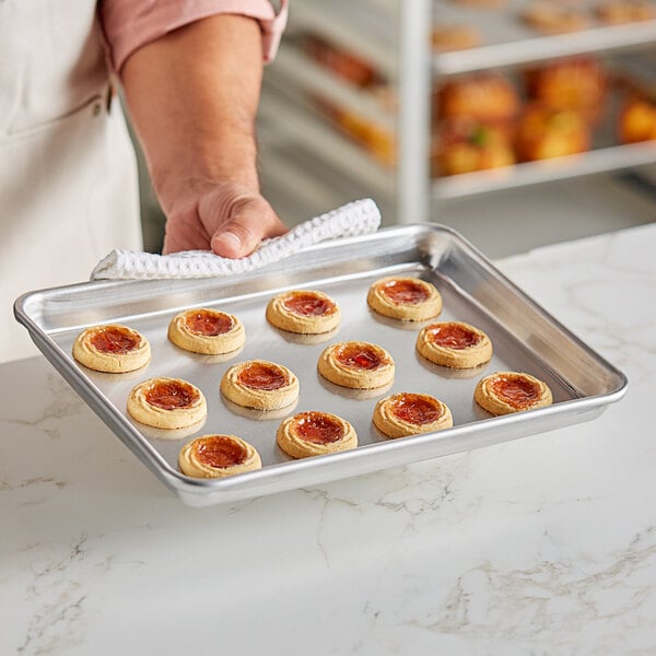 A person holding a Baker's Lane USA bun pan with cookies on it.