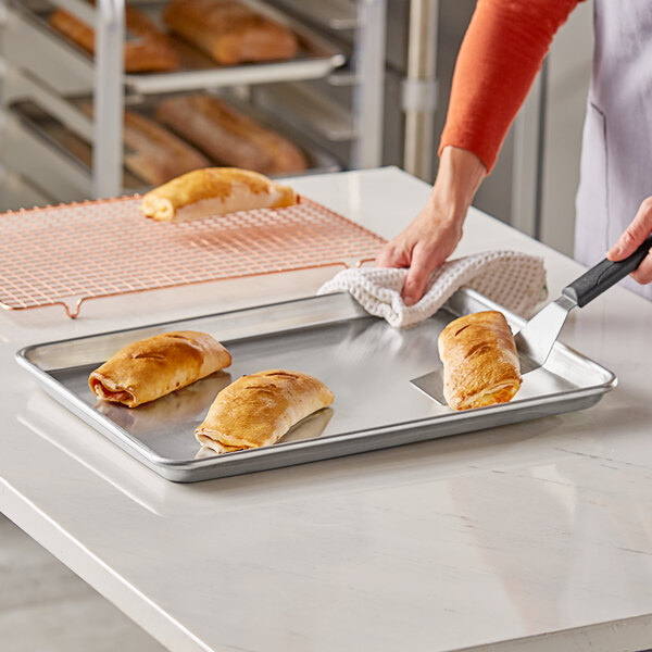 A person using a Baker's Lane aluminum bun pan to bake bread.