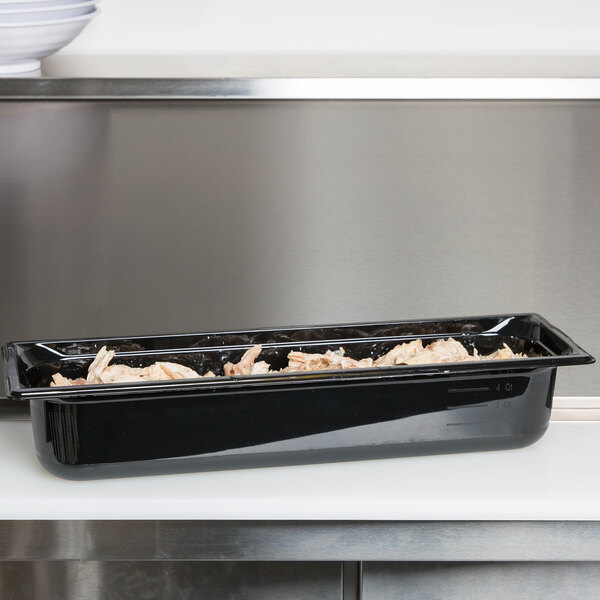 A black plastic Vollrath Super Pan with food in it on a counter.