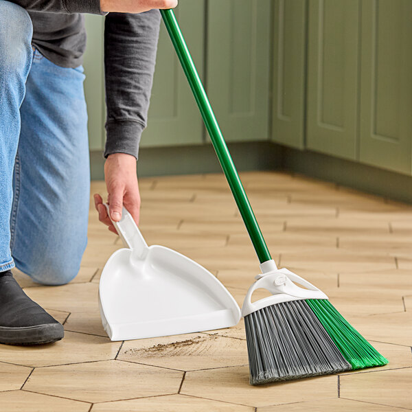A person using a Libman Precision Angle broom to sweep the floor.