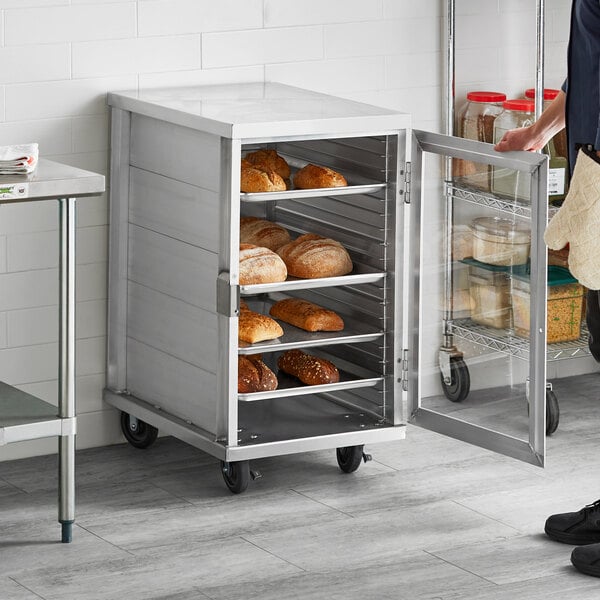 A man standing in front of a metal cabinet with bread in a bakery display.