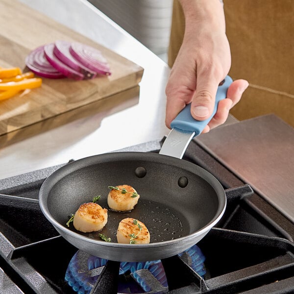 A person cooking scallops in a Vigor A3000 series aluminum frying pan with herbs.