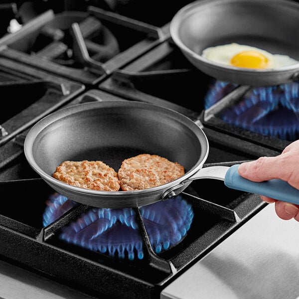 A person using a Vigor aluminum frying pan to cook two fried eggs.