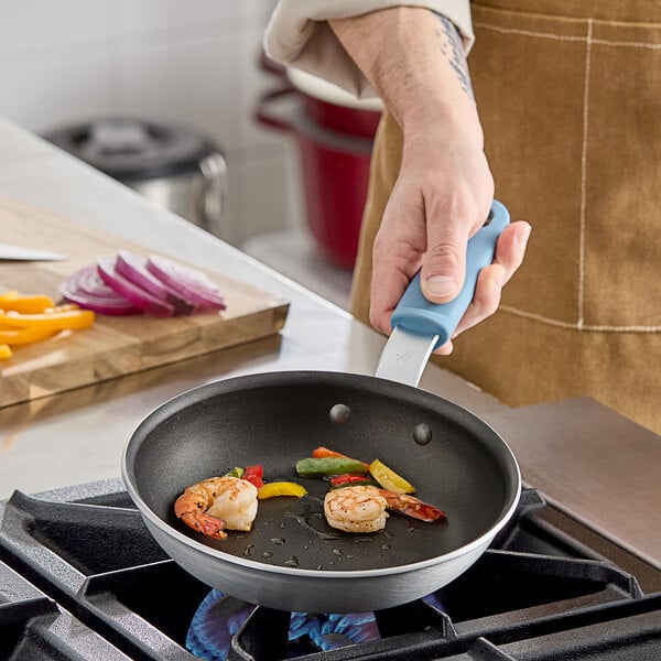 A person cooking shrimp and vegetables in a Vigor A3000 Series aluminum fry pan with QuanTanium non-stick coating.