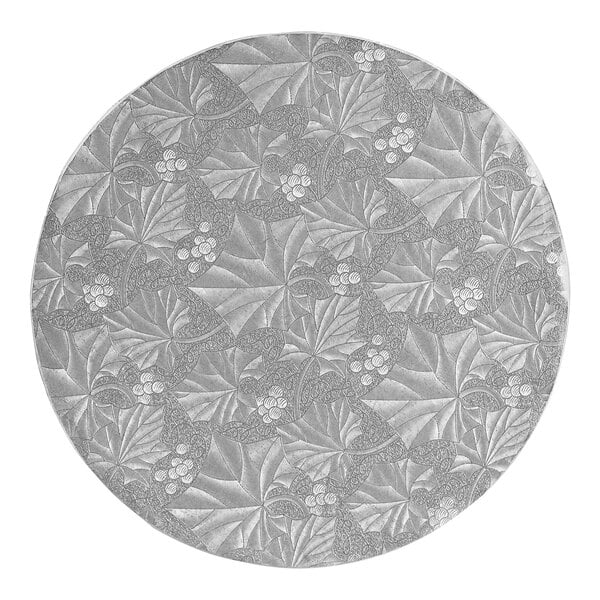 A circular silver cake drum with a pattern of leaves and berries.