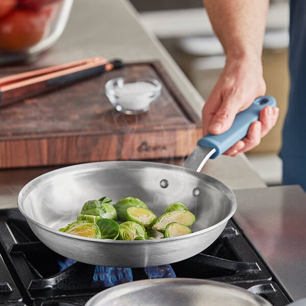 A Vigor A3000 Series aluminum fry pan with brussels sprouts cooking on a stove.