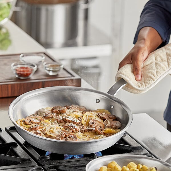 A person cooking food in a Vigor aluminum frying pan.