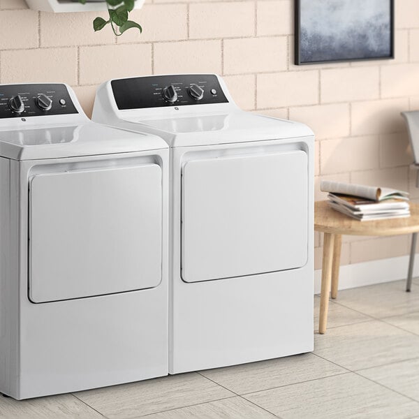 A white GE front load electric commercial dryer with a door.