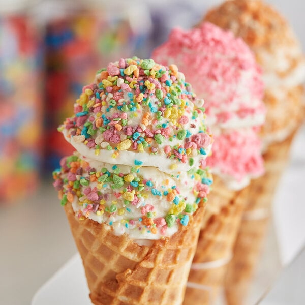 A group of waffle cones with Yum Crumbs Rainbow Fruit topping and colorful sprinkles.