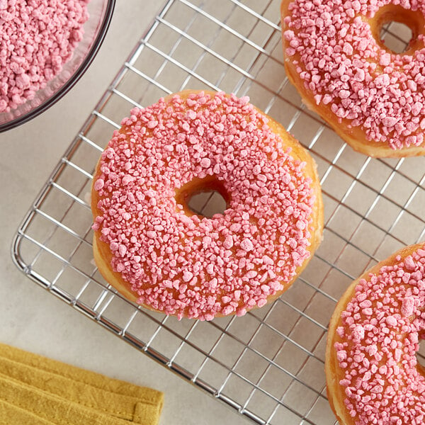 Cherry pie crumb topping on a pink donut with pink sprinkles.