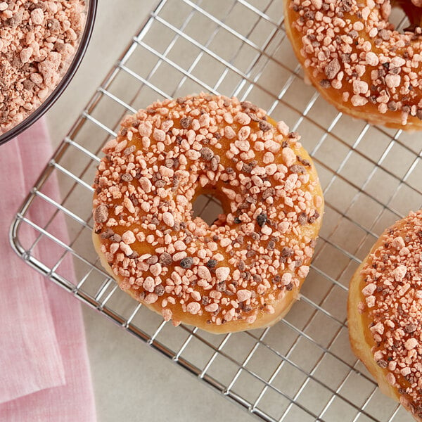 A close-up of a donut with chocolate peanut butter crumb topping and sprinkles.