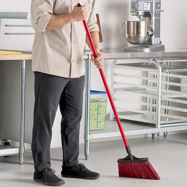 A man in a chef's uniform using a red O-Cedar Commercial broom with unflagged bristles.