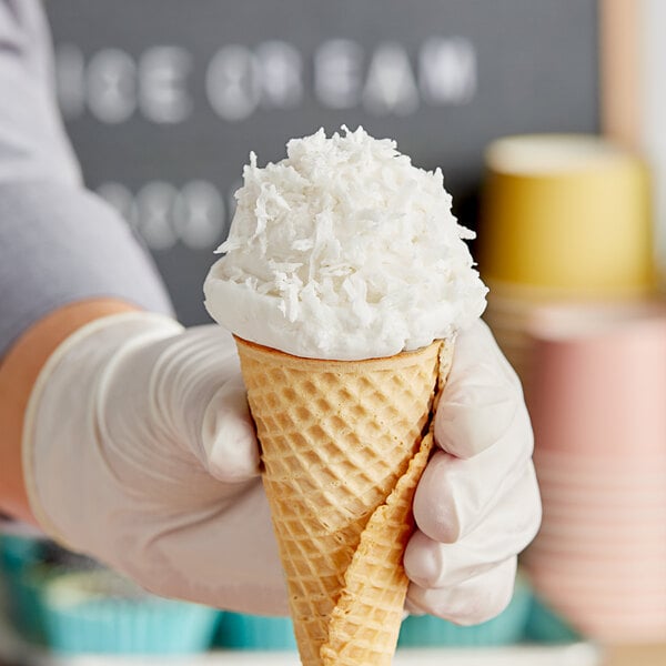 A hand holding an ice cream cone with Embe Organic Coconut Milk Powder in a waffle cone.