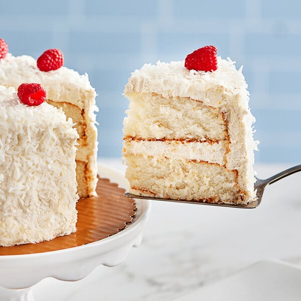 A piece of cake with a raspberry on top on a white plate.