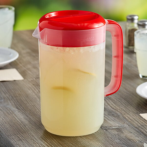 A Choice polypropylene beverage pitcher with a red lid full of lemonade on a table.