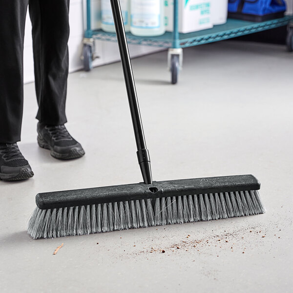 A person sweeping the floor with an O-Cedar commercial broom.