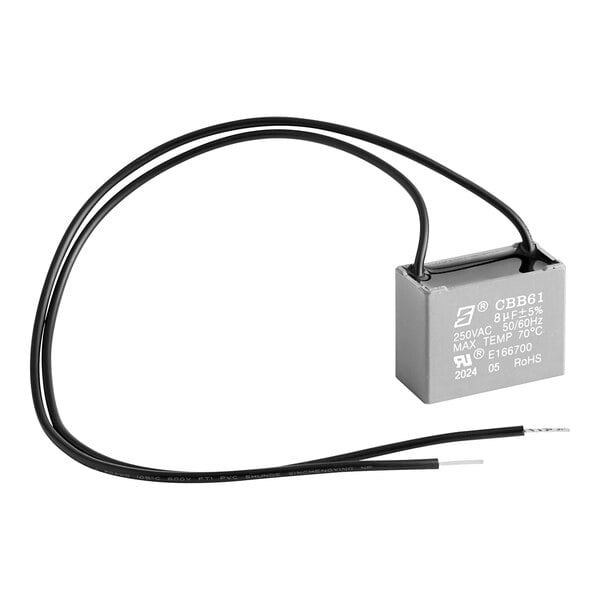 A small grey Noble Products capacitor with black wires.