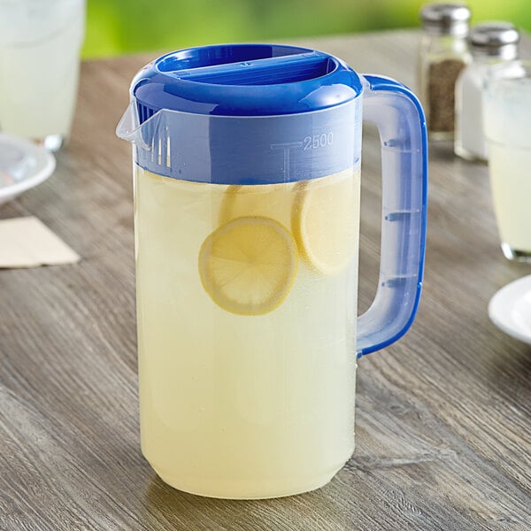 A Choice polypropylene beverage pitcher with lemonade and lemon slices on a white surface.