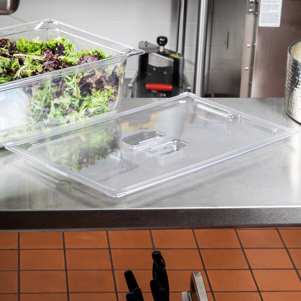 A clear plastic Vollrath Super Pan lid on a counter over food containers.