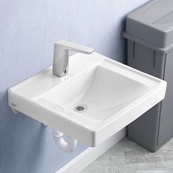 A white American Standard wall-mount lavatory sink with a faucet above it.