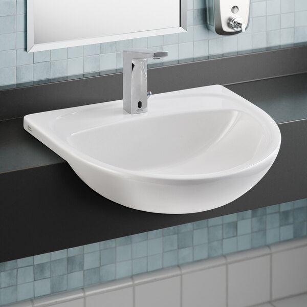 An American Standard white fireclay semi-countertop sink with a silver faucet.