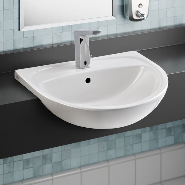 A white American Standard semi-countertop sink with a silver faucet.