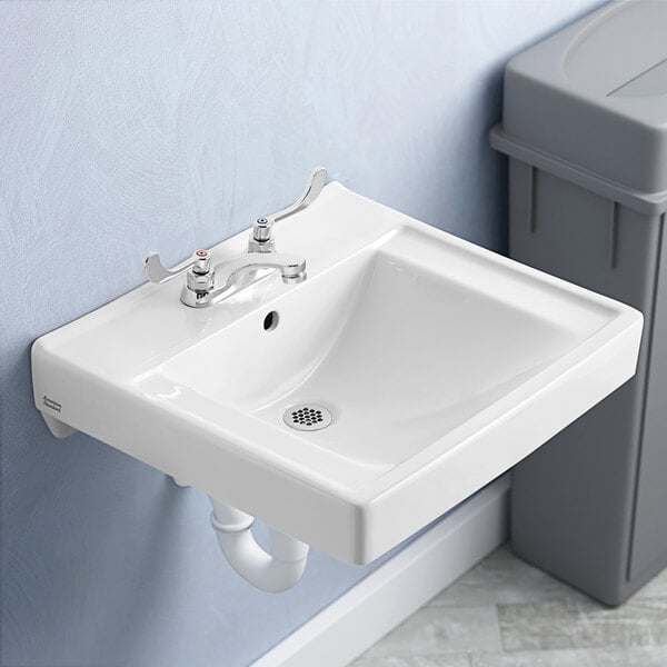A close up of a white American Standard Decorum wall-mount lavatory sink with a drain.