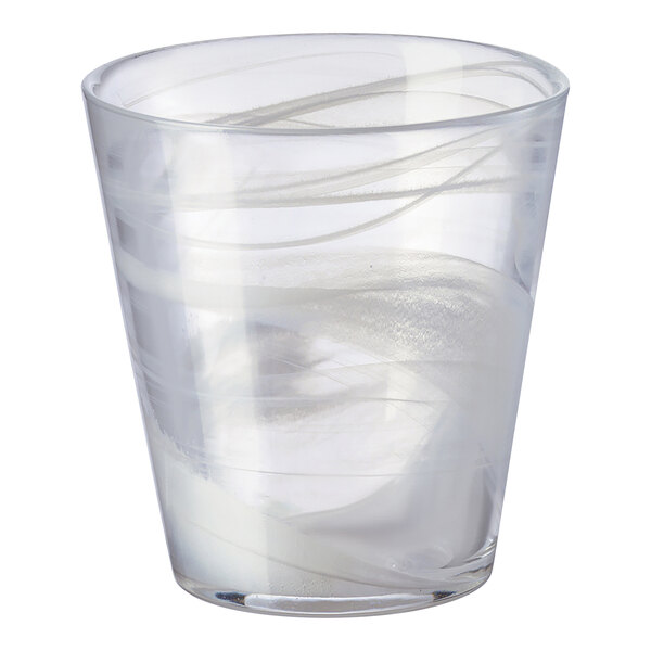 A clear glass with white lines on it full of liquid.