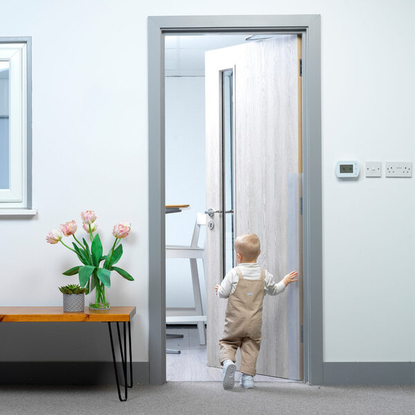 A baby walking through a doorway with a L.A. Baby clear dual shield on the door.