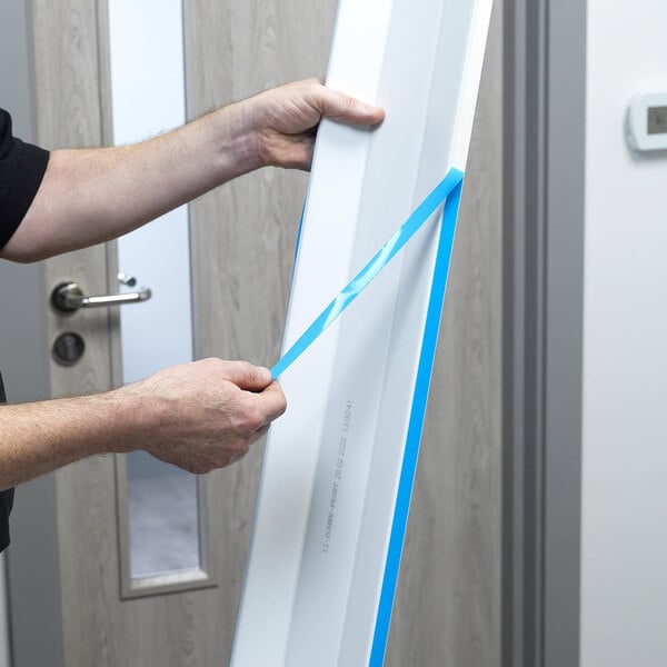 A person using a blue tape measure to measure a door.