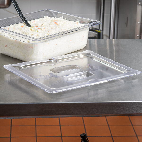 A Vollrath clear plastic slotted lid on a food container on a counter.