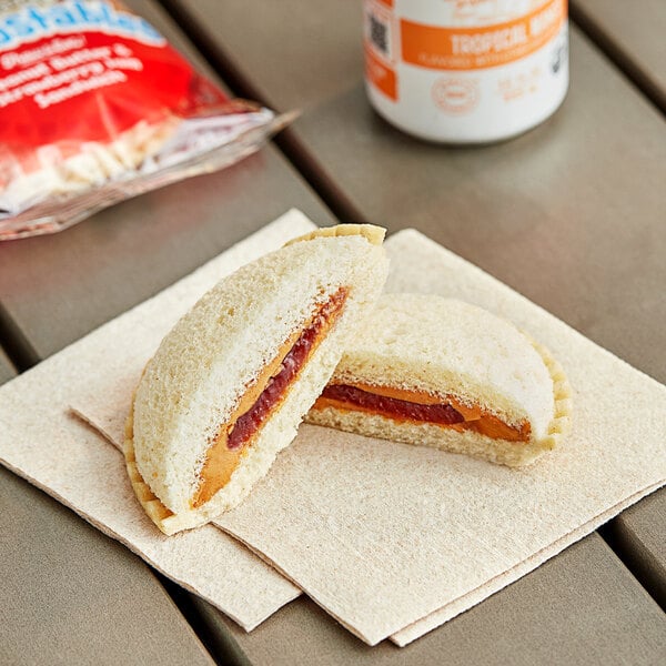 A Smucker's Uncrustables sandwich with peanut butter and jelly on a napkin.