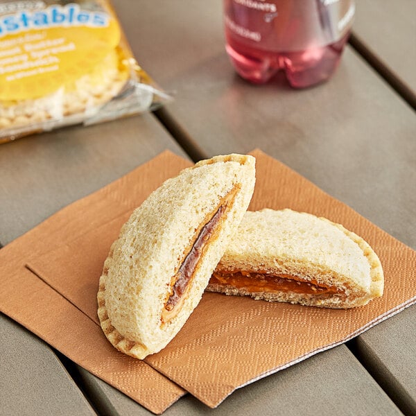 A Smucker's Uncrustables honey and peanut butter sandwich on a napkin.