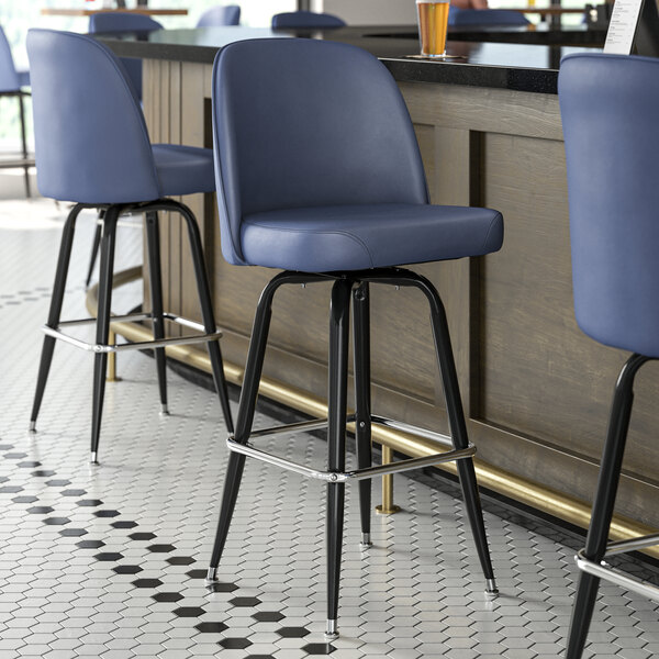 A blue Lancaster Table & Seating bucket seat cushion on a black metal bar stool.