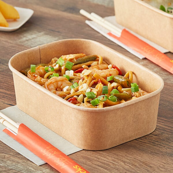 A rectangular Kraft paper take-out container with noodles and chopsticks inside.