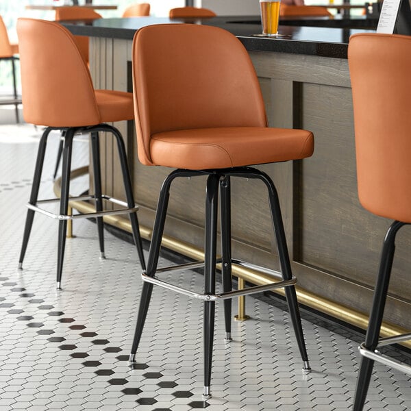 A close up of a Lancaster Table & Seating light brown vinyl bucket seat cushion on an orange chair.