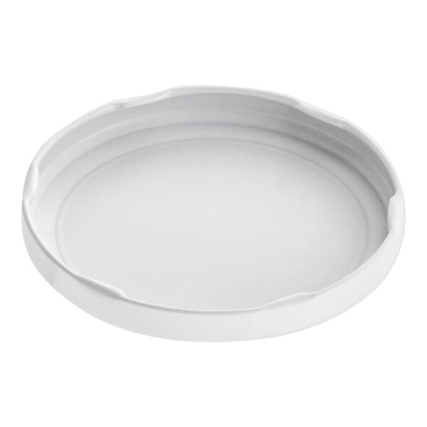 A white metal lid with a circular object on a white surface.
