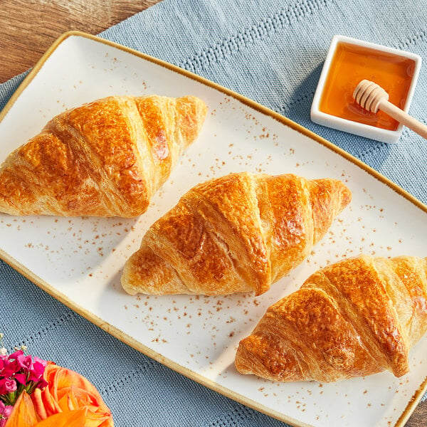 Bridor vegan croissants on a plate with honey and a flower.