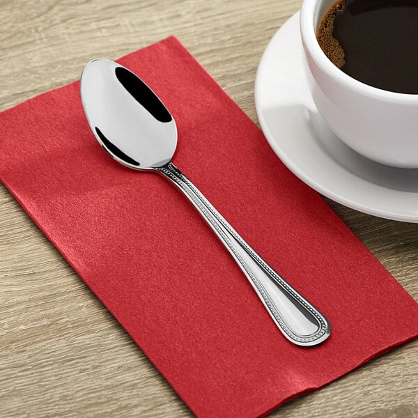 A Choice Milton stainless steel teaspoon on a red napkin.