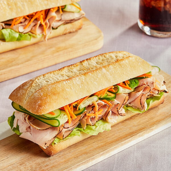 Sliced Bridor ciabatta buns with a sandwich on a cutting board.