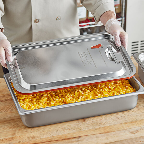 A person holding a metal pan with food inside.