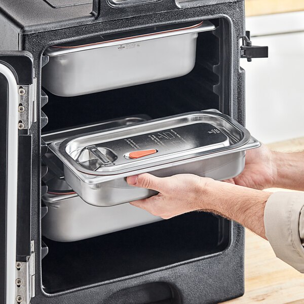 A person opening a Vigor stainless steel hotel pan transport cover.