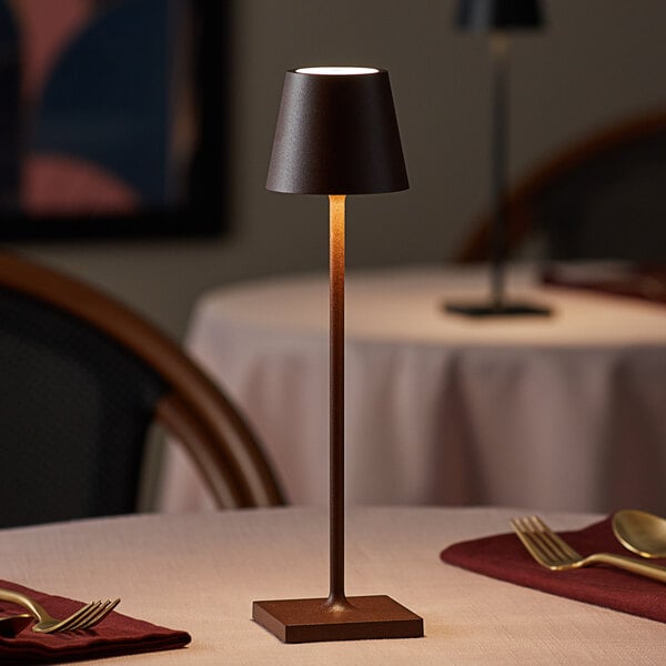 A Zafferano America Poldina Pro table lamp with a brown base on a table.