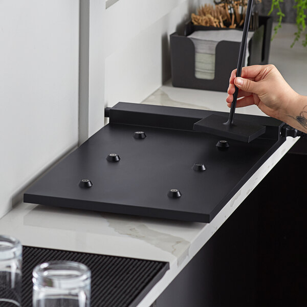 A black rectangular carpet with screws and a glass of water on a counter.