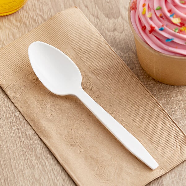 A white heavy weight plastic teaspoon on a napkin.