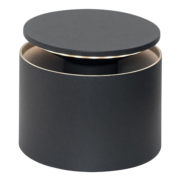 A dark gray cylinder with a round top on a table with lights.