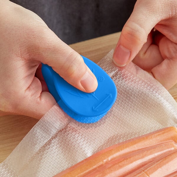 A person using a CrewSafe Viper blue bag opener to remove plastic from sausages.