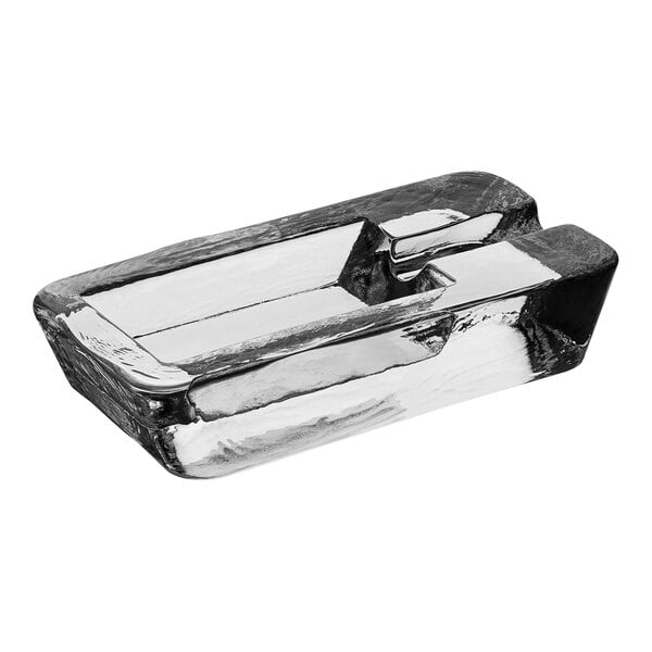 A Crystal glass ashtray with cigarette rests on a counter.